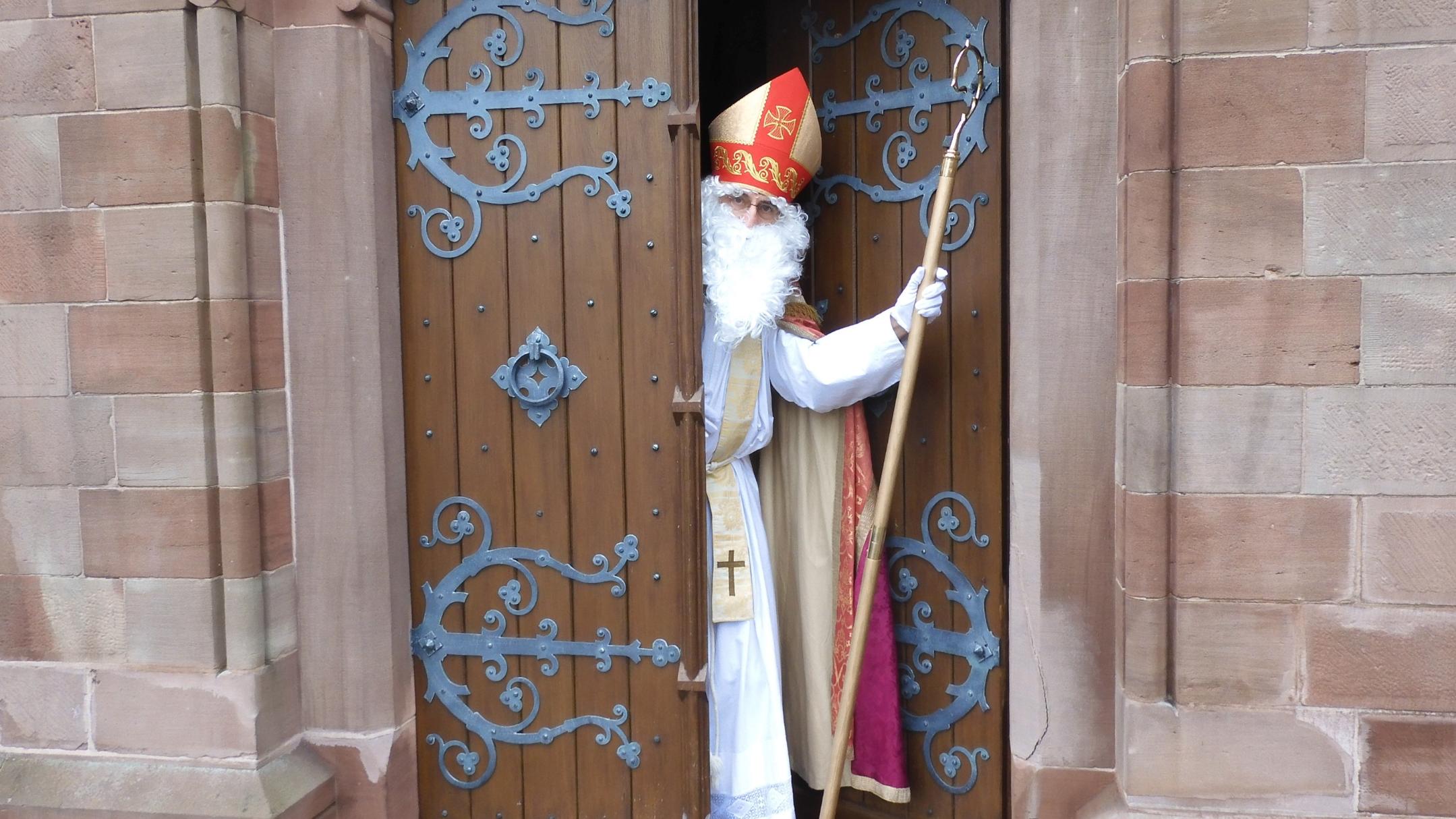 Ein verkleideter Nikolaus kommt aus einer Kirchentüre einem entgegen